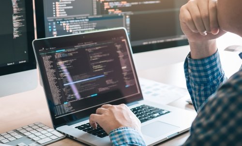 A student considers some coding on a laptop.